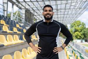 atlético hombre en ropa de deporte soportes con confianza en un abandonado estadio, encarnando fuerza y determinación. foto