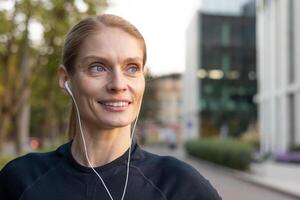 ajuste hembra persona que practica jogging con auriculares sonrisas mientras hacer ejercicio en urbano configuración, capturar un momento de alegría y bienestar. foto