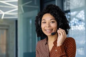 de cerca retrato de mujer de negocios dentro oficina con auriculares teléfono, empleado sonriente y mirando a cámara a lugar de trabajo, llamada centrar cliente servicio. foto