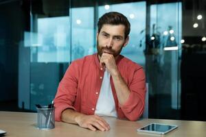 Upset unhappy and sad man inside office at workplace talking with colleagues and partners using call, remote meeting web camera view. photo