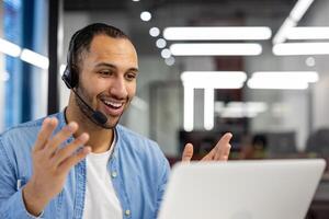 un atractivo cliente Servicio profesional vistiendo un auriculares, trabajando y sonriente en un moderno oficina ambiente. foto