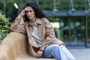 Depressed mature adult woman sitting on bench outside office building, businesswoman boss upset and disappointed with results of achievement at work, bankruptcy and financial loss economic crisis. photo