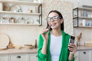 A woman eating a piece of black chocolate, holding a tile in her hands. Eyes closed, enjoying photo