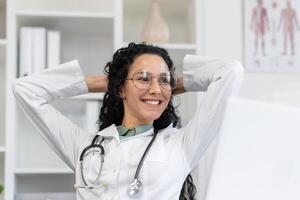 A joyful Latino woman doctor takes a brief break, radiating positivity and confidence in a modern clinic setting. photo