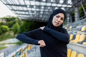 un persona en ropa de deporte sostiene su hombro en dolor, posiblemente lesionado mientras formación en un estadio ajuste. foto