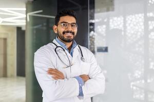 confidente masculino médico con estetoscopio en pie en un clínica con brazos cruzado foto