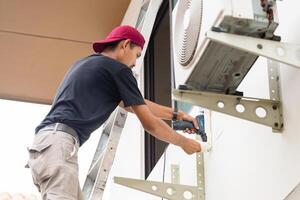 Technician man using a screwdriver to fix and install new air conditioner, repair service, and install new air conditioning concepts photo