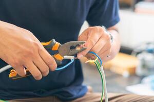 Close-up of Technician cutting electrical wires with pliers for installing new air conditioning, repair service, and install new air conditioner concepts photo