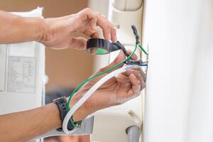 Close-up of Technician hand connecting electric wires to install new air conditioning, repair service, and install new air conditioner concepts photo