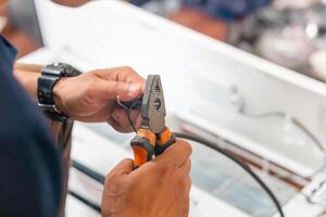 Close-up of Technician cutting electrical wires with pliers for installing new air conditioning, repair service, and install new air conditioner concepts photo