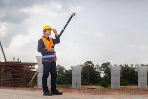 capataz trabajador comprobación proyecto a edificio sitio, ingeniero, y constructores en sombreros duros en construcción sitio foto