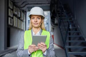 retrato de un joven hembra ingeniero, constructor, arquitecto vistiendo un difícil sombrero, reflexivo chaleco y participación un tableta. él mira seriamente dentro el cámara. foto