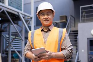 un profesional industrial trabajador vistiendo un alta visibilidad chaleco sostiene un tableta mientras en pie a un industrial sitio. foto