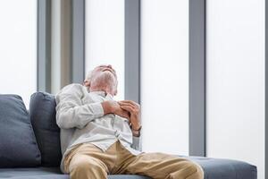 Senior man presses hand to chest has heart attack suffers from unbearable pain, Man with pain on heart in living room photo