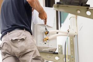 Technician man using a wrench to fix modern air conditioning system, Maintenance, repair and install new air conditioner photo