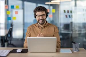 Smiling Hispanic businessman using a headset during a business call in a modern office environment. Professional, engaged, and focused. photo