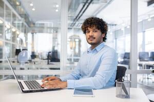 enfocado profesional comprometido en trabajo en un ordenador portátil a un brillante, contemporáneo oficina con un abierto espacio disposición. foto