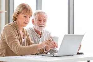 Worried senior couple checking their bills, retired elderly old family reading documents photo