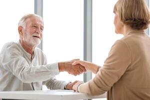 Woman handshaking greeting senior man client, Health visitor, and a senior man during a home visit photo