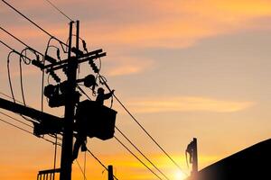 Silhouette of Electrician officer climbs a pole and uses a cable car to maintain a high voltage line system, Shadow of Electrician lineman repairman worker at climbing work on electric post power pole photo