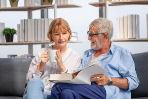 Senior man and woman reading a book and enjoying coffee, Cheerful couple spending time together in the living room photo