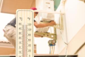 Thermometer with blurred technician install new air conditioner background, Hot temperature photo