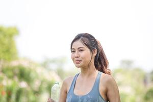 Asian sportswoman cools down by pouring fresh water, female fitness pouring water over her perfect body photo
