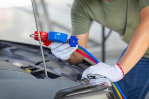 Technician man checks car air conditioning system refrigerant recharge, Repairman holds monitor tool to check and fix car air conditioner system photo