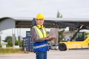 Engineer man with laptop in industry containers cargo, Foreman dock worker in hardhat and safety vest control loading containers box from cargo photo