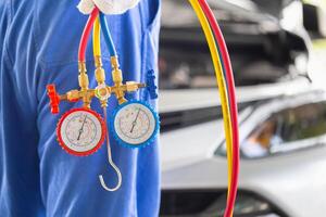 Repairman holds monitor tool to check and fix car air conditioner system, Technician checks car air conditioning system refrigerant recharge, Car Air Conditioning Repair photo