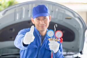 Repairman showing thumbs up and holding monitor tool to check and fixed car air conditioner system, Technician check car air conditioning system photo