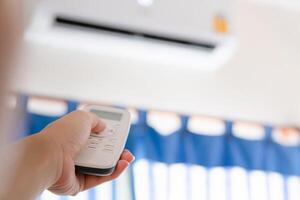 Hand with air conditioner remote controller, Woman holding remote air conditioner turning on cooler system photo