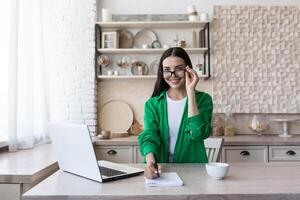 un joven hembra alumno, un persona de libre dedicación estudios, trabajos en línea, remotamente a hogar desde un ordenador portátil foto