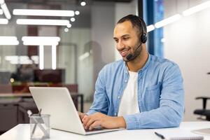 contento masculino cliente Servicio agente con un auriculares trabajando a un computadora en un moderno oficina configuración, atractivo en cliente apoyo. foto