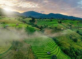 Landscape of rice terrace and hut with mountain range background and beautiful sunrise sky. Nature landscape. Green rice farm. Terraced rice fields. Travel destinations in Chiang Mai, Thailand. photo