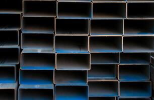 Industrial warehouse stock of rectangular metal pipes for building and construction supplies. Stack of steel pipes. Iron materials for construction and infrastructure projects. Steel tubing storage. photo