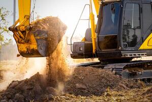 Close-up of excavator at construction site. Backhoe digging soil for earthwork and construction business. Excavating machine at work. Heavy machinery for earth moving and construction site development photo