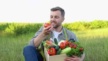 Happy farmer holding basket with fresh harvested vegetables and smiling in camera on countryside field. Concept. biological, bio products, bio ecology, vegetarian and vegan video