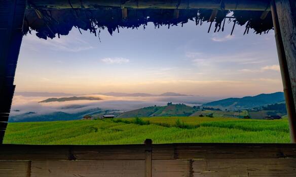 A view of a field with a foggy sky and mountains in the background. The sky is a mix of blue and orange hues, creating a serene and peaceful atmosphere. Rice terrace farm field and mountains. photo