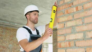 ingenieur maatregelen van de verticaal afwijking van de muur. bubbel niveau heerser dichtbij omhoog visie, meten en nivelleren concept video