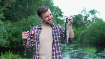 pescador sostiene el trucha atrapado en el río. trucha pesca. pescar en el río video