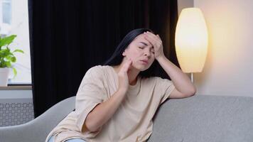 mujer teniendo un dolor de cabeza a hogar en sofá. sensación estresado. video