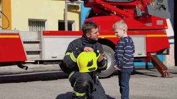 Little boy with firefighter in protective uniform in fire station video