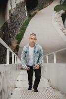 A man in a denim jacket and black pants is walking up a set of stairs photo