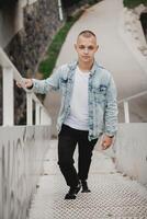 un joven hombre en un blanco camisa y azul chaqueta es posando en un conjunto de escalera foto