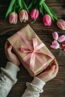 Mother's Day theme. Mother's hands offer daughter gift with tulips and pink ribbon. photo