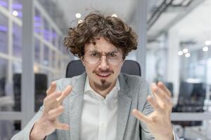 Focused young adult businessman with curly hair working at his office desk. Professional corporate atmosphere with a touch of dynamism. photo