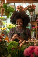 joven negro mujer es en pie en su propio flor comercio, sonriente a su teléfono como ella gestiona el flor Tienda foto
