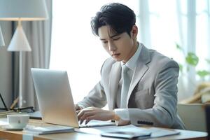 young korean man sitting with her laptop in workspace photo