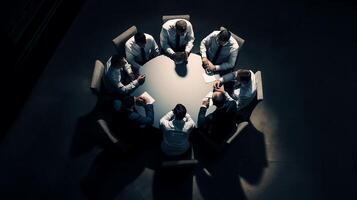 a group of businessmen sits around a round table at a business convention in the midst of a dimly lit room photo